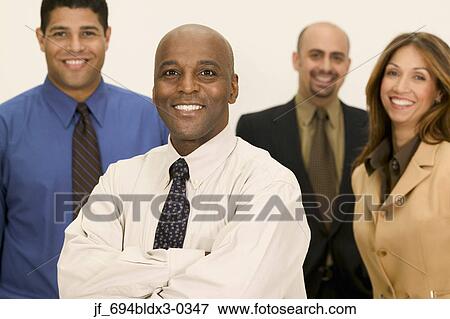 Stock Photo - Group of young business executives standing together looking at camera smiling. Fotosearch