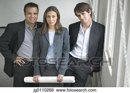 Two young businessmen and a young businesswoman looking at camera View Large Photo Image Stock Photo - Two young businessmen and a young businesswoman looking at camera. Fotosearch