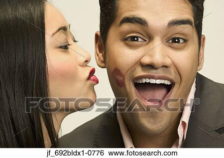 Stock Photograph - Young woman kissing a young man on the cheek. Fotosearch