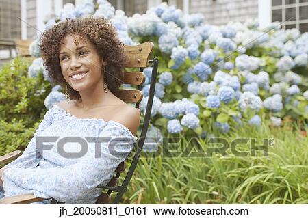 Stock Image - Young woman relaxing in a lawn chair. Fotosearch