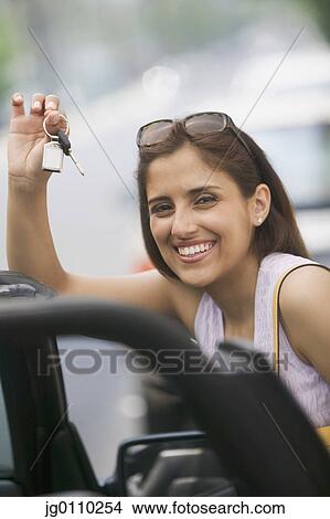 Picture - Woman smiling holding keys in her hand smiling. Fotosearch