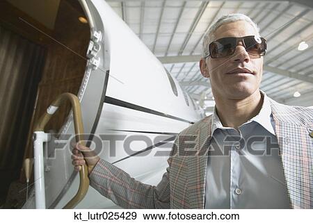 Stock Photo - Middle-aged man boarding airplane in hanger, Nobato, California, United States. Fotosearch