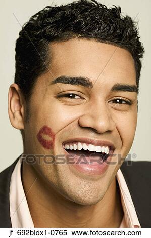 Stock Photography - Young man smiling with a lip stick mark on his cheek. Fotosearch