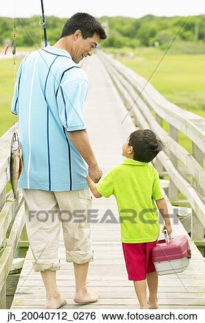 Father and son walking on a pier holding fishing gear View Large Photo Image Stock Photograph - Father and son walking on a pier holding fishing gear. Fotosearch