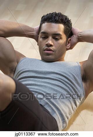 Stock Photo - High angle view of a young man exercising on the floor. Fotosearch