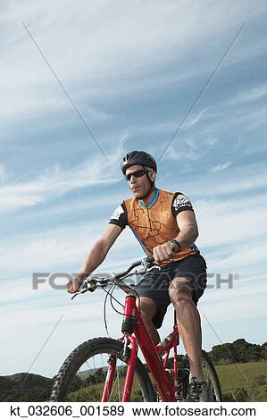 Stock Photo - Male cyclist riding under blue sky, California, United States. Fotosearch