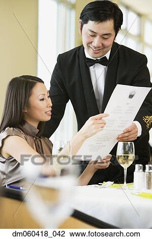 Stock Image - Asian businesswoman ordering meal in restaurant. Fotosearch