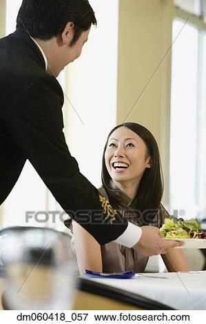 Stock Photo - Asian woman being served in restaurant. Fotosearch