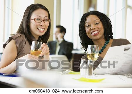 Picture - Two businesswomen smiling in restaurant. Fotosearch