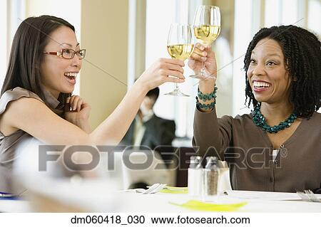 Stock Image - Two businesswomen toasting in restaurant. Fotosearch