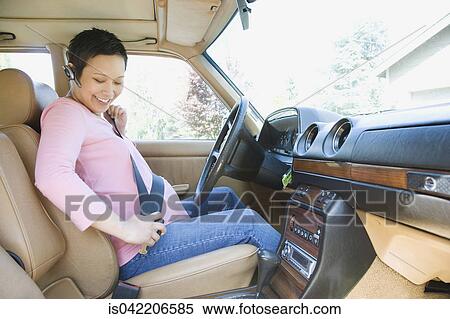 Stock Photography - Pregnant woman putting on seatbelt in car. Fotosearch