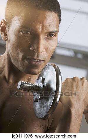 Close-up of a young man lifting a dumbbell View Large Photo Image Stock Photograph - Close-up of a young man lifting a dumbbell. Fotosearch