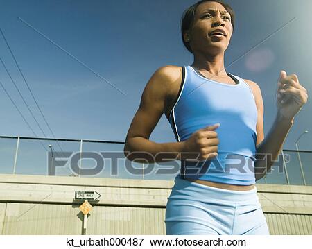 Stock Photo - Female athlete running in urban surroundings. Fotosearch