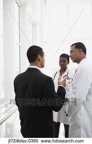 Stock Photography - Doctors talking to businessman. Fotosearch