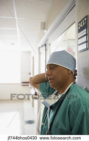 Stock Image - Middle-aged Indian male surgeon rubbing back of his head, Bethesda, Maryland, United States. Fotosearch