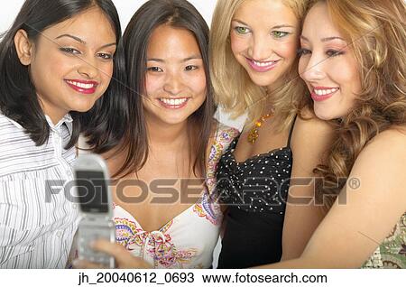 Group of young women standing together looking at a mobile phone smiling View Large Photo Image Stock Image - Group of young women standing together looking at a mobile phone smiling. Fotosearch