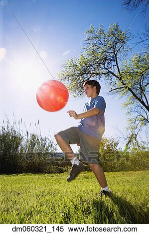 Boy kicking ball in bright sunlight View Large Photo Image Stock Photography - Boy kicking ball in bright sunlight. Fotosearch