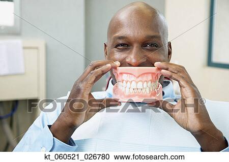 African man in dentist's chair holding up model of teeth View Large Photo Image Stock Image - African man in dentist's chair holding up model of teeth. Fotosearch