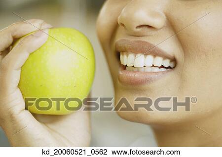 Close up of woman holding apple next to her mouth View Large Photo Image Stock Image - Close up of woman holding apple next to her mouth. Fotosearch