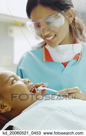 Indian female dental assistant working on African boy View Large Photo Image Stock Image - Indian female dental assistant working on African boy. Fotosearch