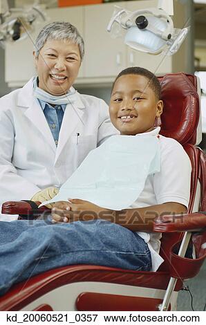 Senior Asian female dentist and African boy in dentist's chair View Large Photo Image Stock Photo - Senior Asian female dentist and African boy in dentist's chair. Fotosearch
