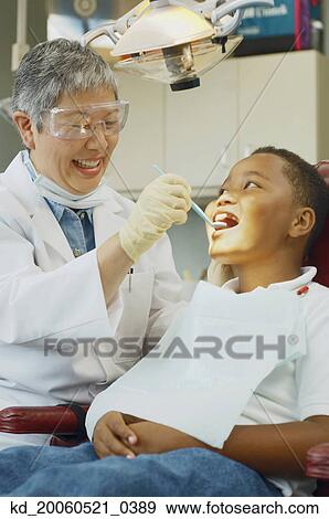 Senior Asian female dentist and African boy in dentist's chair View Large Photo Image Stock Photo - Senior Asian female dentist and African boy in dentist's chair. Fotosearch