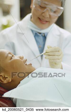 Senior Asian female dentist working on African boy View Large Photo Image Stock Photography - Senior Asian female dentist working on African boy. Fotosearch