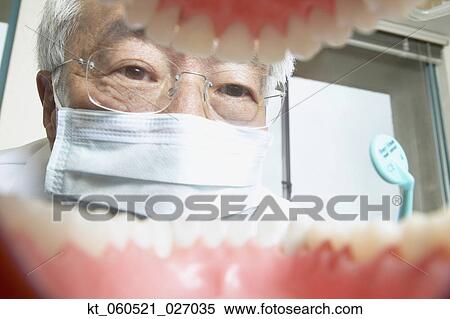 Shot from mouth looking out at senior Asian male dentist View Large Photo Image Stock Photography - Shot from mouth looking out at senior Asian male dentist. Fotosearch
