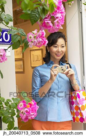 Stock Photo - Mid adult woman holding a camera. Fotosearch