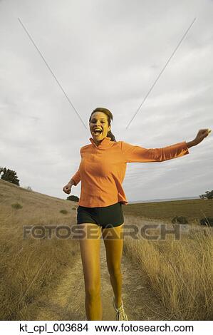 Picture - Portrait of woman jogging in field. Fotosearch