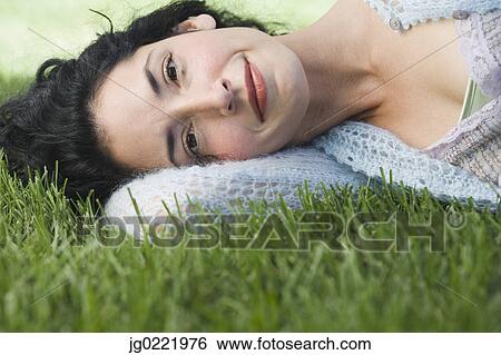 Stock Photograph - Young woman laying on grass. Fotosearch