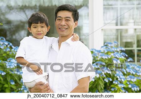 Mid adult man standing holding a young boy View Large Photo Image Stock Photo - Mid adult man standing holding a young boy. Fotosearch