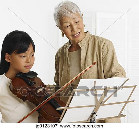 Stock Photo - Senior Asian woman teaching young Asian girl violin. Fotosearch