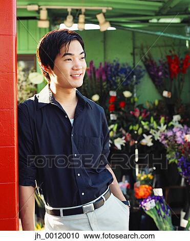 Young man standing in a flower shop View Large Photo Image Stock Image - Young man standing in a flower shop. Fotosearch