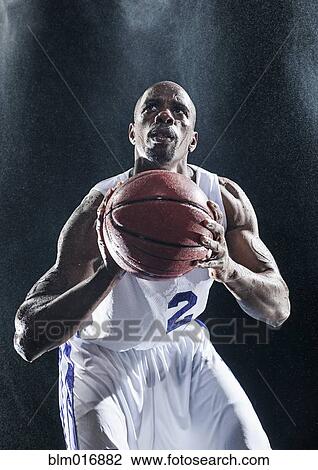 Stock Image - African American basketball player standing in rain. Fotosearch