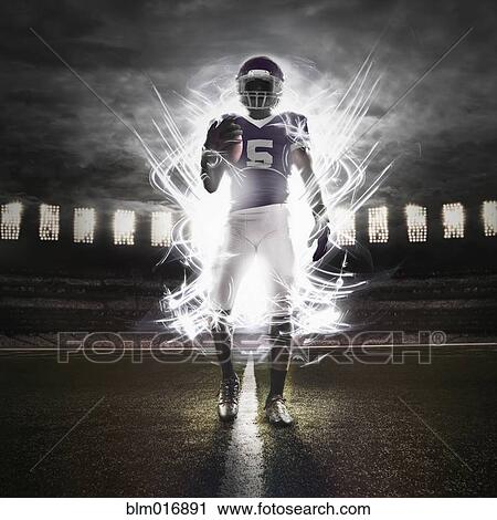Stock Image - African American football player illuminated on field. Fotosearch