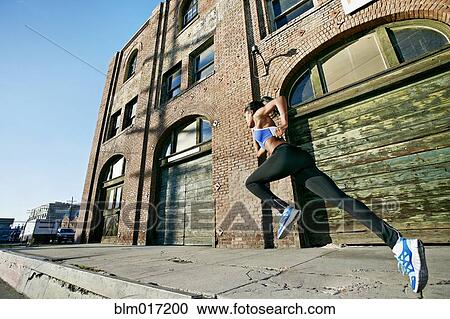 Stock Image - Black woman running on city street. Fotosearch