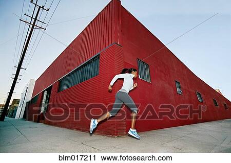Stock Image - Black woman running on city street. Fotosearch