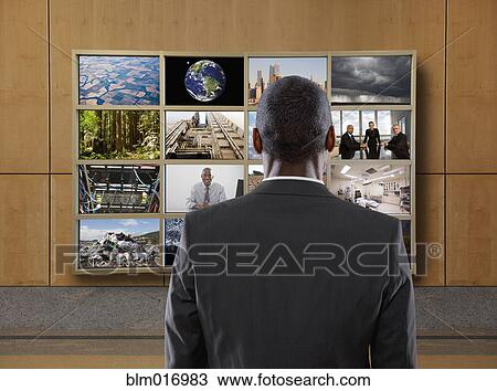 Stock Image - Businessman watching collage screen in office. Fotosearch