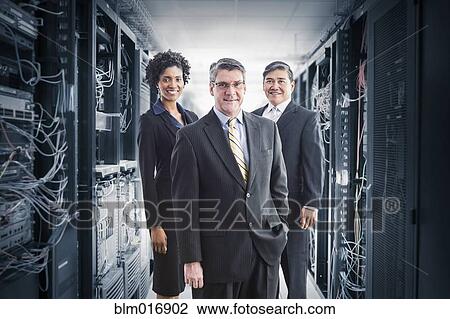 Stock Image - Businesspeople smiling in server room. Fotosearch