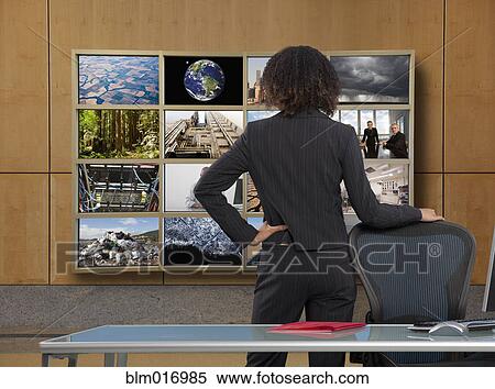 Businesswoman watching collage screen in office View Large Photo Image Stock Photography - Businesswoman watching collage screen in office. Fotosearch