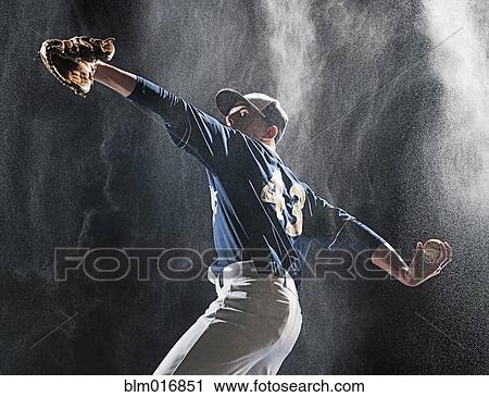 Stock Image - Caucasian baseball player pitching in rain. Fotosearch