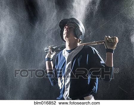 Stock Image - Caucasian baseball player standing in rain. Fotosearch