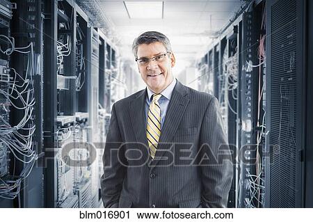 Stock Image - Caucasian businessman smiling in server room. Fotosearch