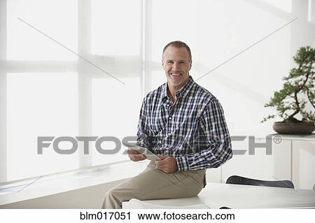 Stock Image - Caucasian businessman using tablet computer in office. Fotosearch