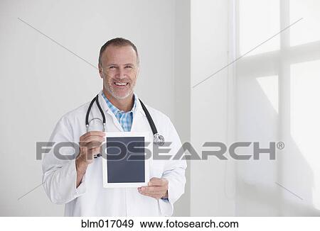 Stock Photo - Caucasian doctor holding tablet computer in office. Fotosearch