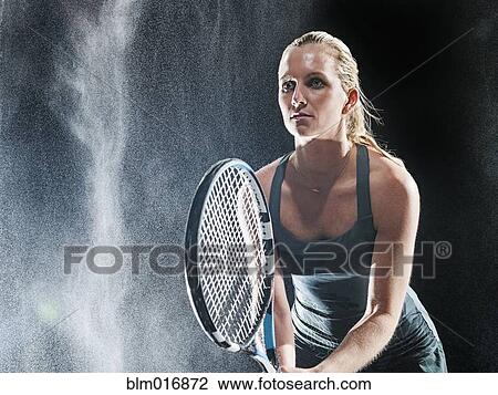 Stock Image - Caucasian tennis player standing in rain. Fotosearch