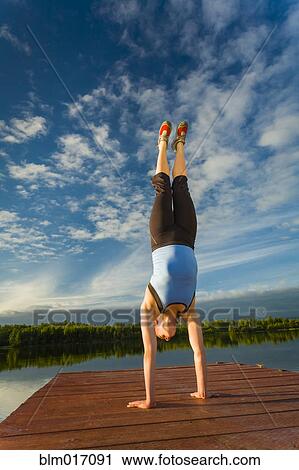 Stock Image - Caucasian woman practicing yoga on dock on still lake, Anchorage, Alaska, United States. Fotosearch