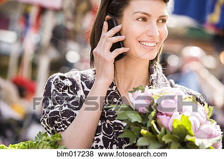Caucasian woman talking on cell phone at market View Large Photo Image Stock Photo - Caucasian woman talking on cell phone at market. Fotosearch