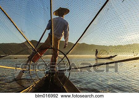 Stock Image - Fisherman rowing canoe on water. Fotosearch